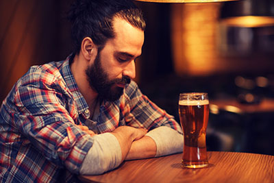 человек смотрит на стакан пива